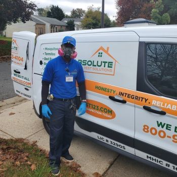 Pest control technician beside Absolute Pest Solutions van outside a home for bedbug extermination